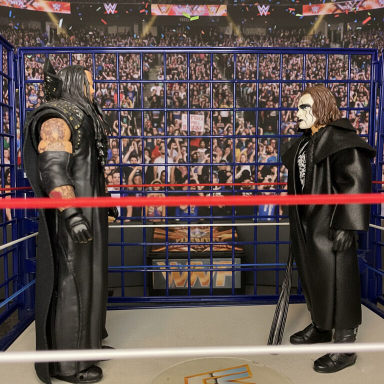 Seite an Seite: Sting Crow Persona und Undertaker Classic Deadman Actionfiguren mit schwarzen Trenchcoats.