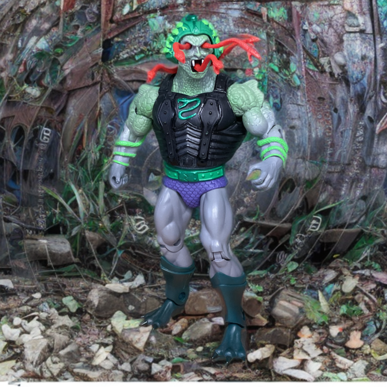 Snake Face MOTU-Figur mit herausspringenden Schlangen im Gesicht, grüner Rüstung und schaurig leuchtenden Kapuzenaugen.