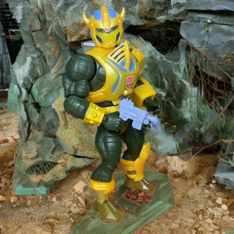 Masters of the Universe Origins Bumblebee Armor Man-At-Arms Actionfigur mit Blastergewehr und heruntergeklapptem Visier in Kampfpose.