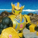Imagen de héroe destacada de la figura de acción Hombre de Armas Armadura de Bumblebee de Masters del Universo Orígenes con la armadura amarilla completa de Bumblebee, pose heroica frontal para el artículo de reseña.