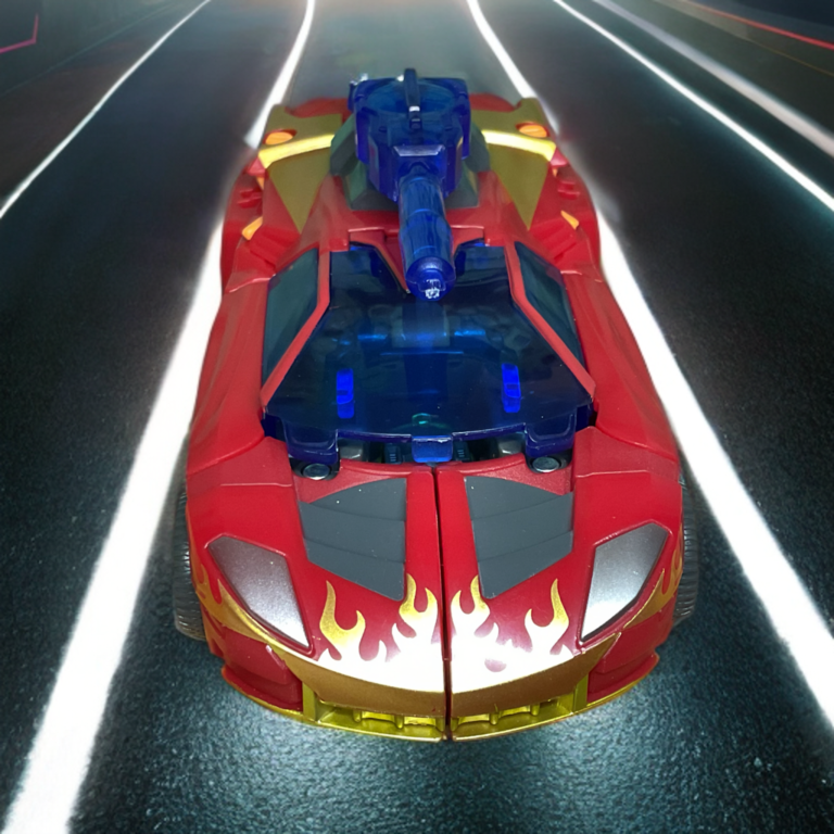 Overhead shot of Age of the Primes Excellion in vehicle mode highlighting gold flames, orange spoiler wings, and blue cannon detail.