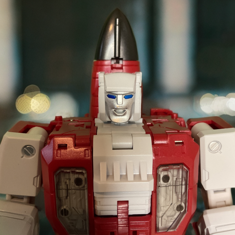 Close-up detail shot of Zeta Toys Fly Fire Metallic Edition robot mode head and chest, metallic yellow visor eyes and flame detailing on arms.