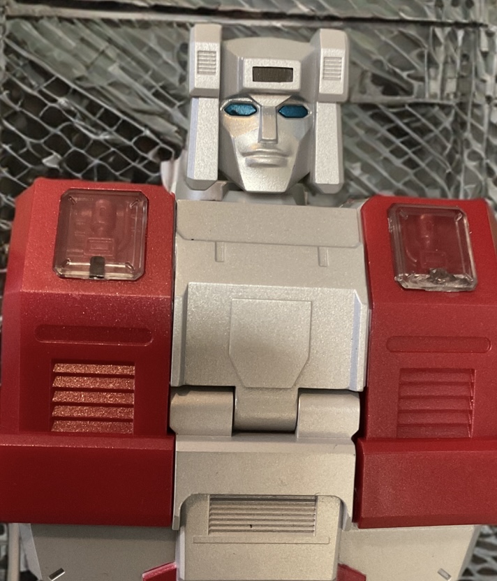 Close-up detail shot of Zeta Toys Silver Arrow Metallic Edition robot mode head and chest, visor helmet with metallic blue eyes and premium paint applications.