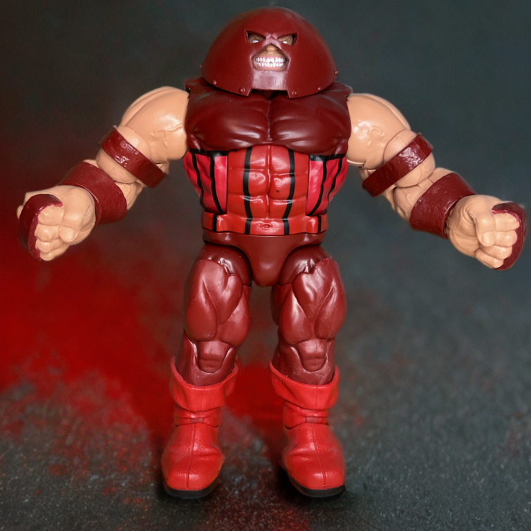 Figurine Juggernaut de Marvel Legends en armure et casque cramoisis, posée de façon dynamique pour mettre en valeur sa taille immense et son élan imparable.