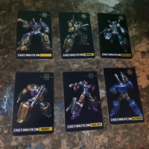 Collection of colorful Transformers-style trading cards with character artwork, profiles, and details spread on a surface.