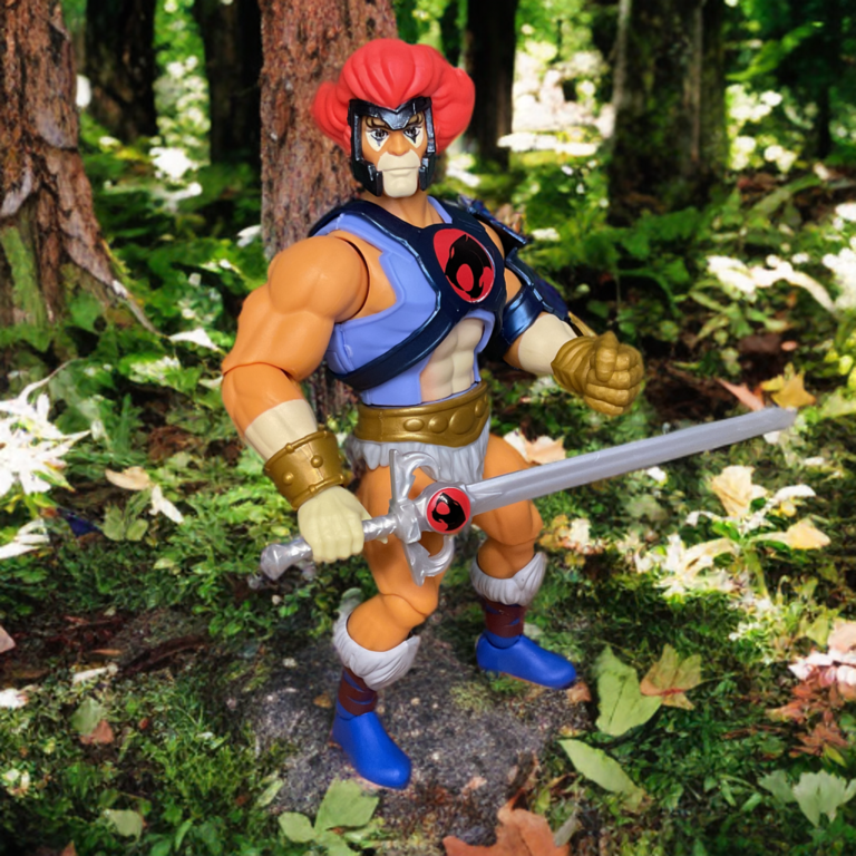MOTU Origins crossover Lion-O figure in golden autumn forest, leaves falling, holding Sword of Omens aloft in heroic pose.