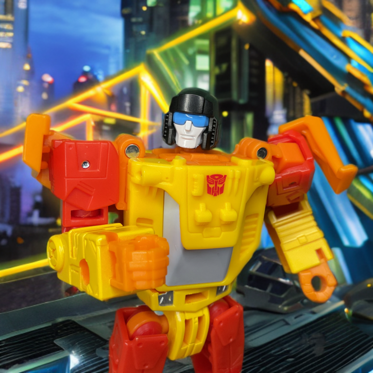 Vista de perto, da cintura para cima, do Transformers Age of the Primes Deluxe Sureshot no modo robô, mostrando a parte superior do corpo vermelha e amarela, o símbolo Autobot no peito, o capacete preto com visor azul e a armadura de ombro detalhada.