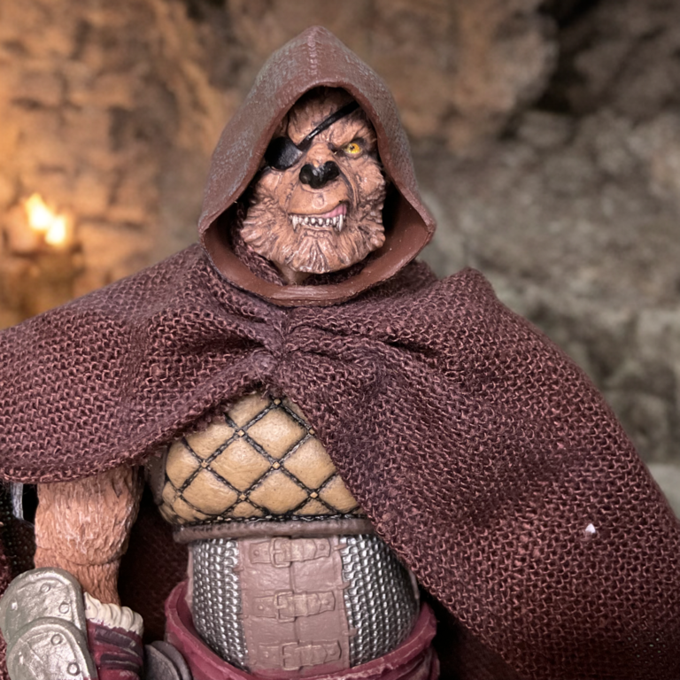 Primer plano de la cara de la figura Jaeger del Crisol Salvaje mostrando el parche en el ojo, la expresión gruñona, el pelaje marrón texturizado y la armadura metálica del hombro.