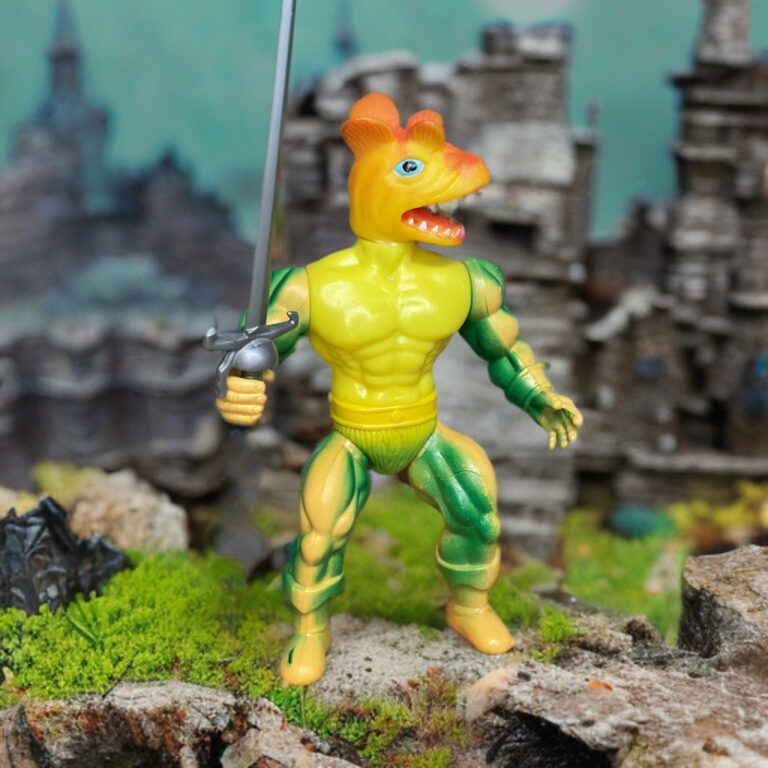 Pose curvada da figura do Zardus de Remco 1982, cabeça de inseto demoníaco com mandíbulas, olhos compostos vermelhos, antenas curvadas, peito segmentado semelhante a uma armadura, mãos com garras, acessório de espada prateada e postura agressiva pronta para atacar.