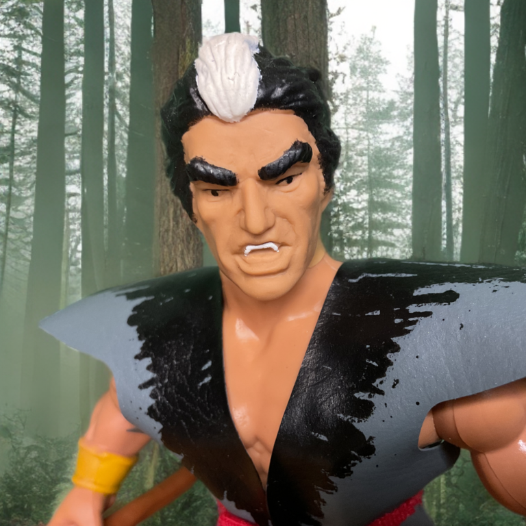 A tight shot of the Mikola figure's face, highlighting the painted fangs and the stern, focused expression.