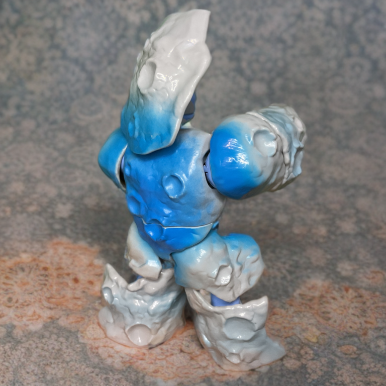 Foto de perfil da figura de ação Stonedar MOTU Origins na Fantasy Action Figures, mostrando a armadura detalhada e os tons de pele azuis.