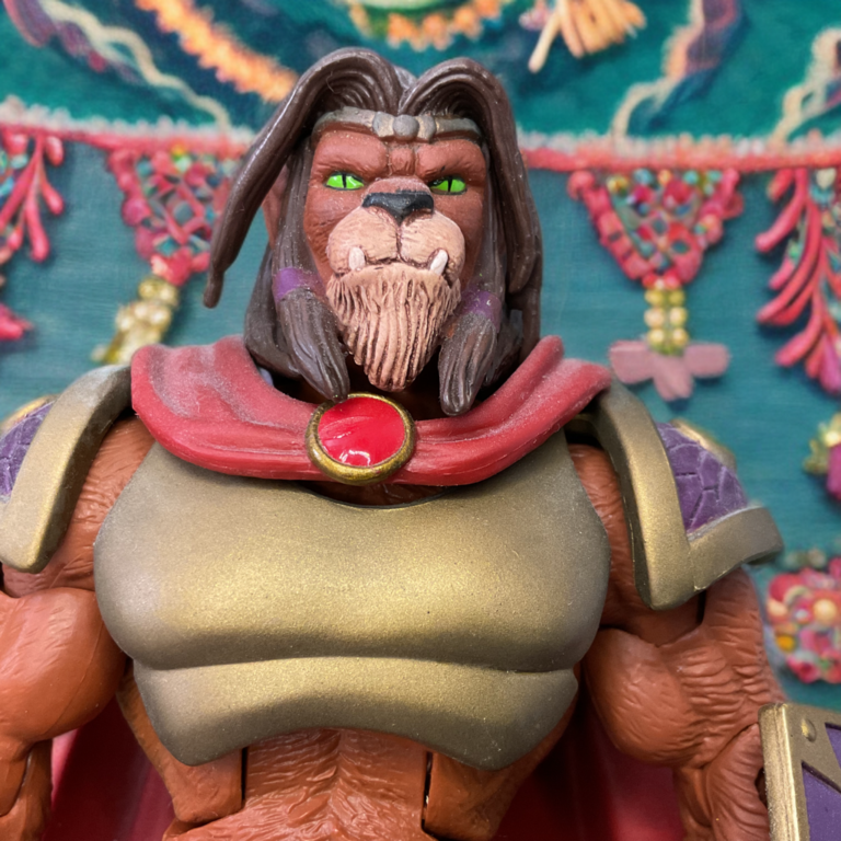 MOTUC Häuptling Carnivus Actionfigur in einer dramatischen Bergdorfkulisse, Wächter von Felis Qadi.