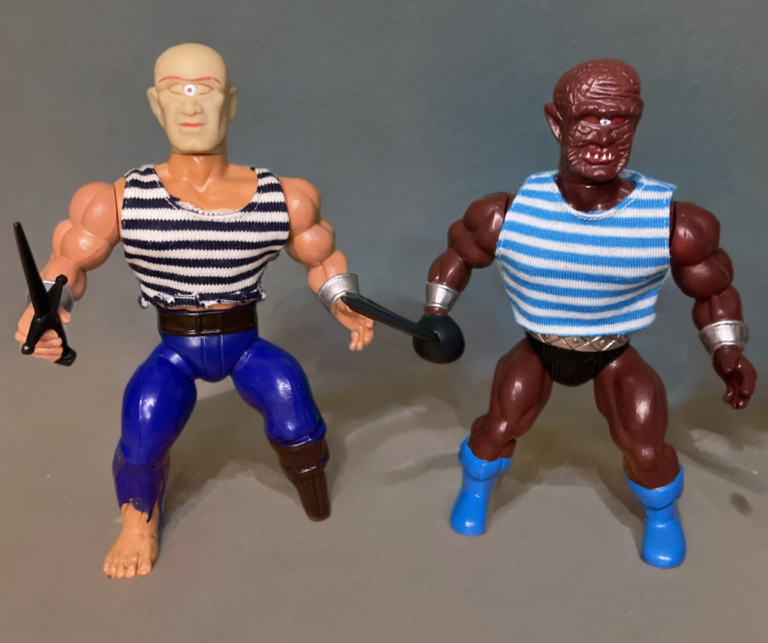 A crisp, side-by-side studio photograph of two 5.5-inch action figures against a solid, neutral light grey background. On the left is the vintage 1983 Remco Peg Leg figure, featuring an asymmetrical build with a brown plastic peg leg, green skin, and a single cyclopean eye on his forehead. On the right stands the modern Zoloworld Mad Eyed Marauder figure, showcasing a highly detailed zombie pirate sculpt with mismatched bulging eyes, intricate paint detailing, and modern articulation seams.