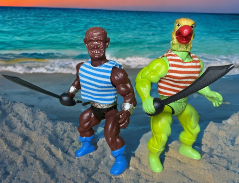 A close-up, ground-level photograph of two retro-style action figures on a sandy beach.