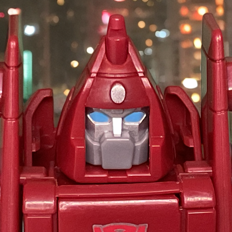 Ultra close-up of the Powerglide figure’s face mask and eyes, highlighting the detailed silver paint finish.