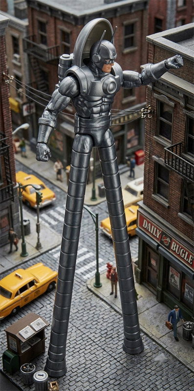 A high-angle shot of a Stilt-Man action figure standing on incredibly long, segmented metallic legs that extend down to a cobblestone street. The silver-armored villain reaches out toward a brick building wall, looking down at classic yellow taxi cabs, a newspaper kiosk, and miniature human figures on the sidewalks below.